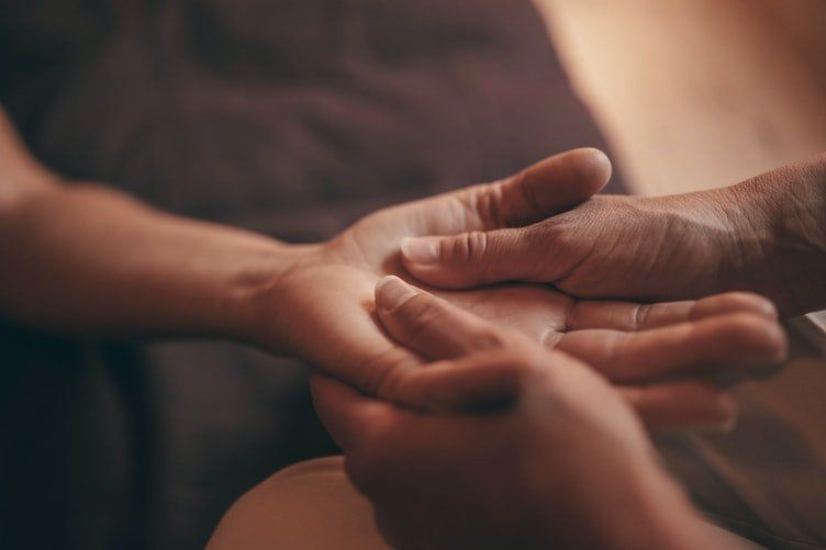 Two hands gently holding an open palm in soft, warm light