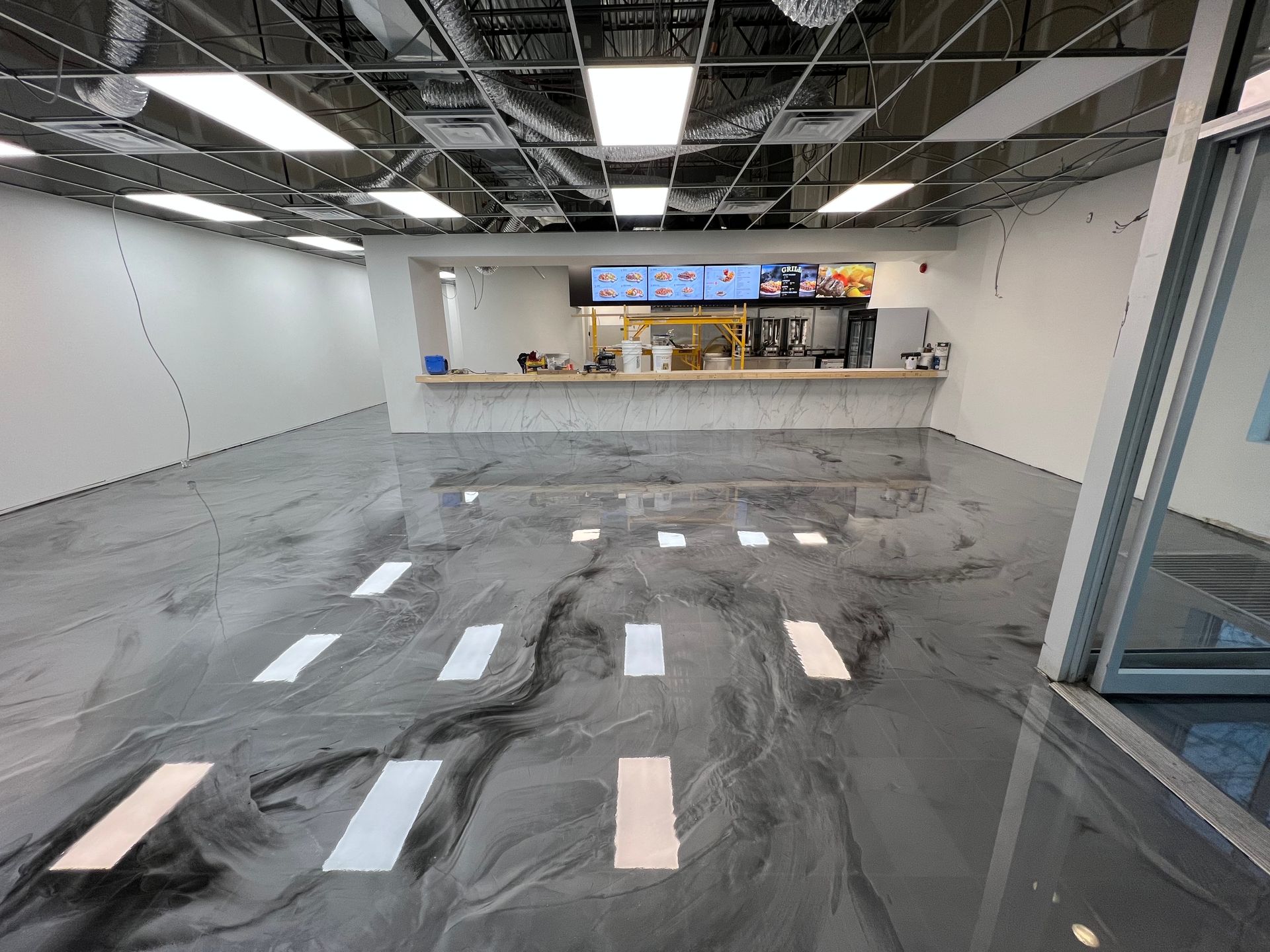 Interior shot of a newly constructed food establishment with a reflective epoxy floor and serving counter.