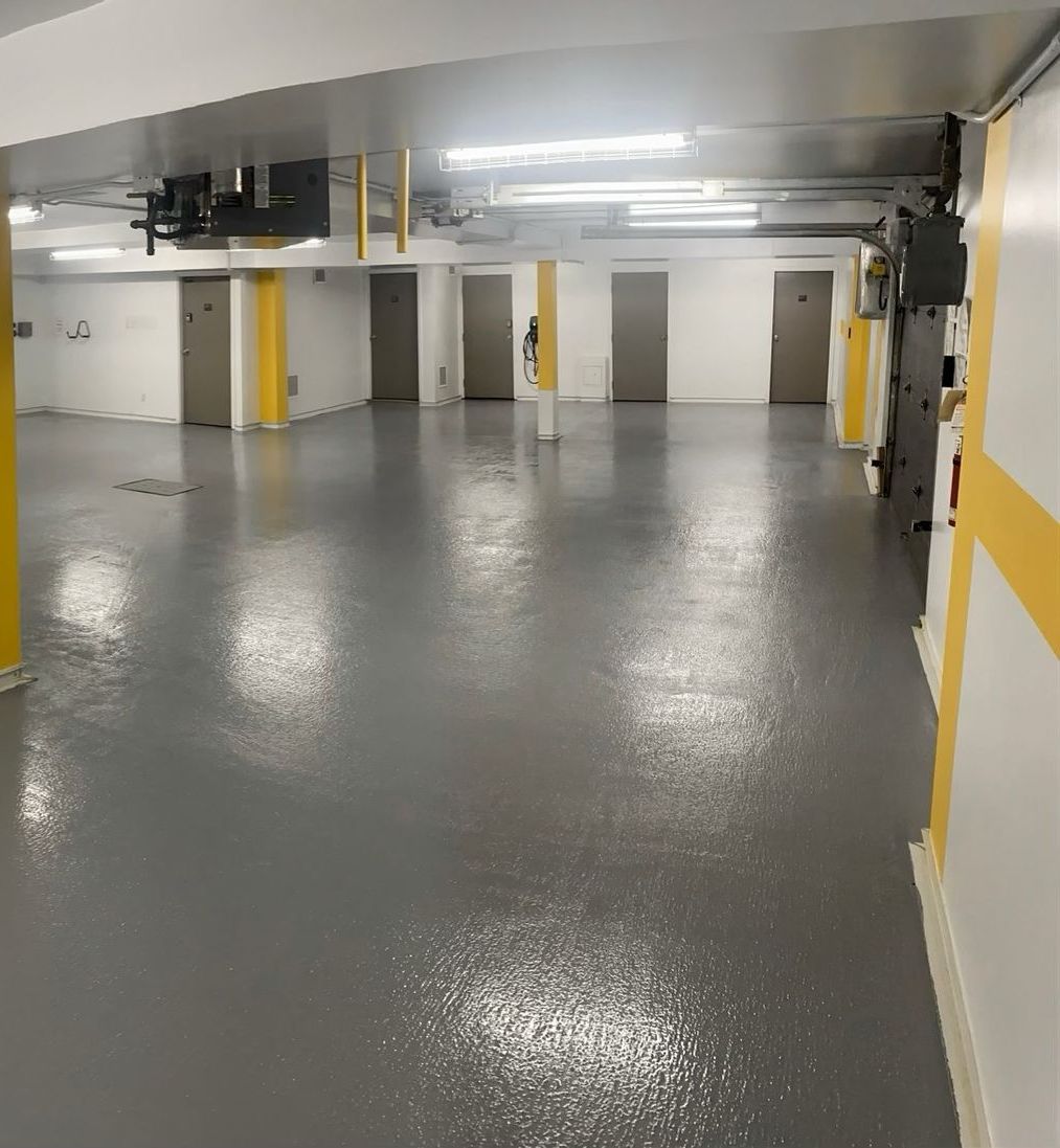 Grey and yellow painted interior of a building, with multiple doors and overhead lights.