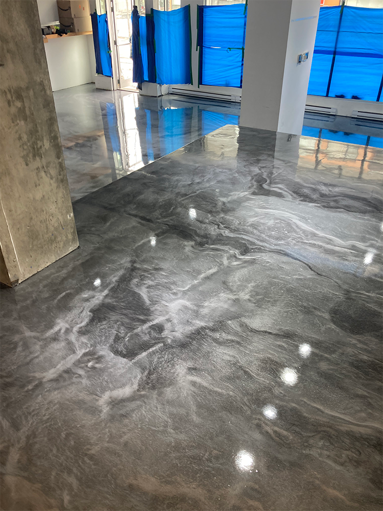 Gray and silver metallic epoxy flooring reflecting light in an open, bright room.