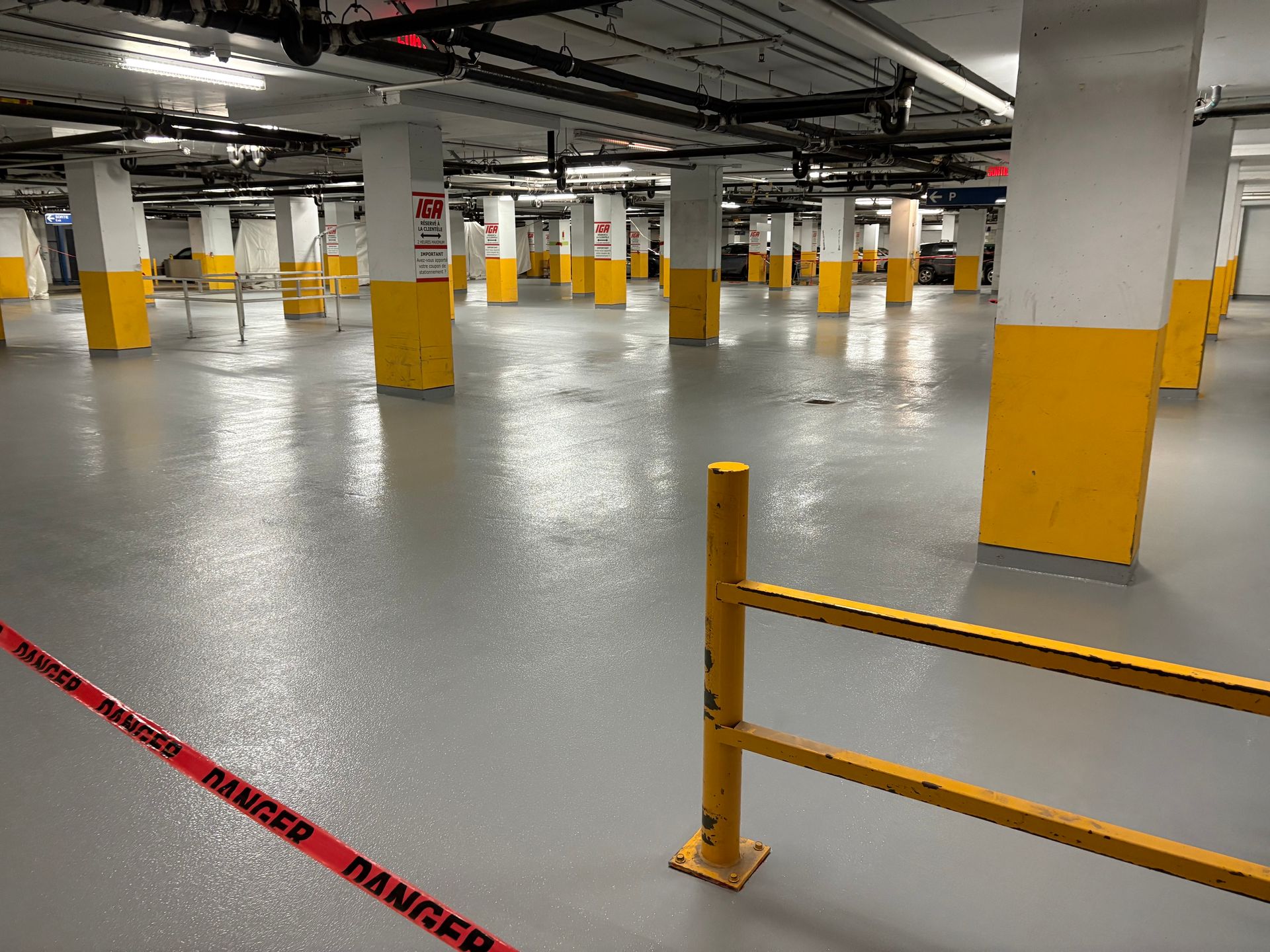 Indoor parking garage with yellow and white columns, wet gray floor, and a red