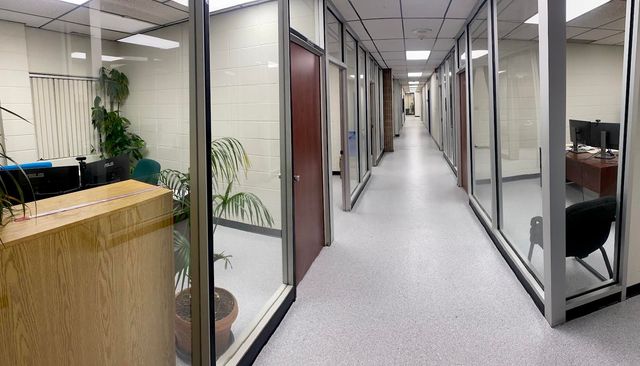 Un long couloir avec des murs en verre dans un immeuble de bureaux