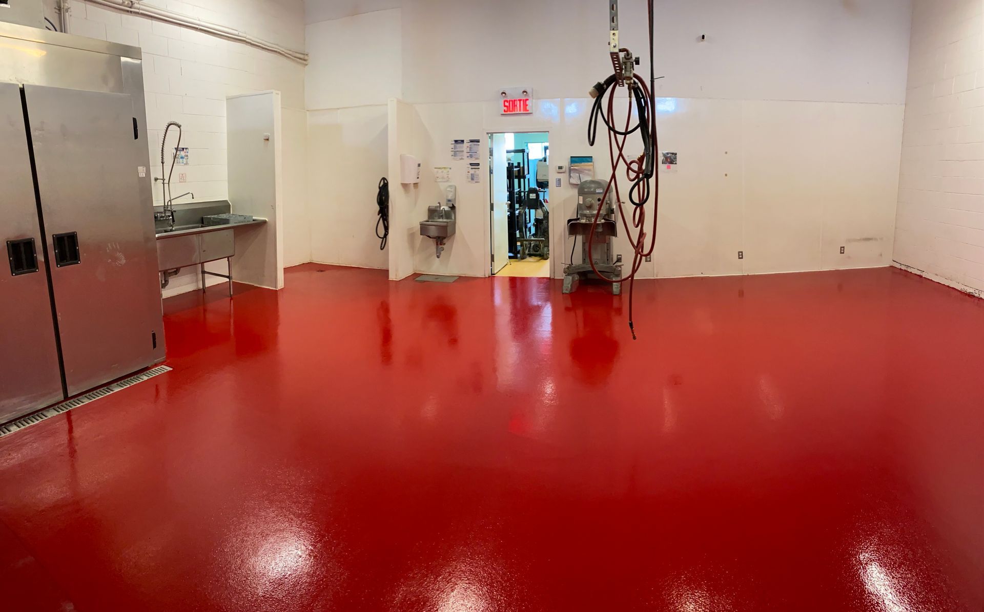 Red epoxy floor in a medical room with stainless steel cabinets, and medical equipment.