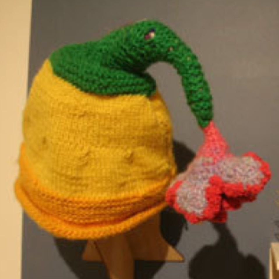 A yellow hat with a green top and a red flower on it