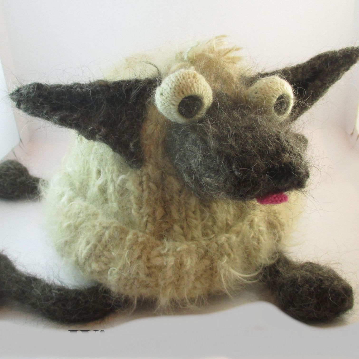 A stuffed sheep with big eyes and a pink tongue