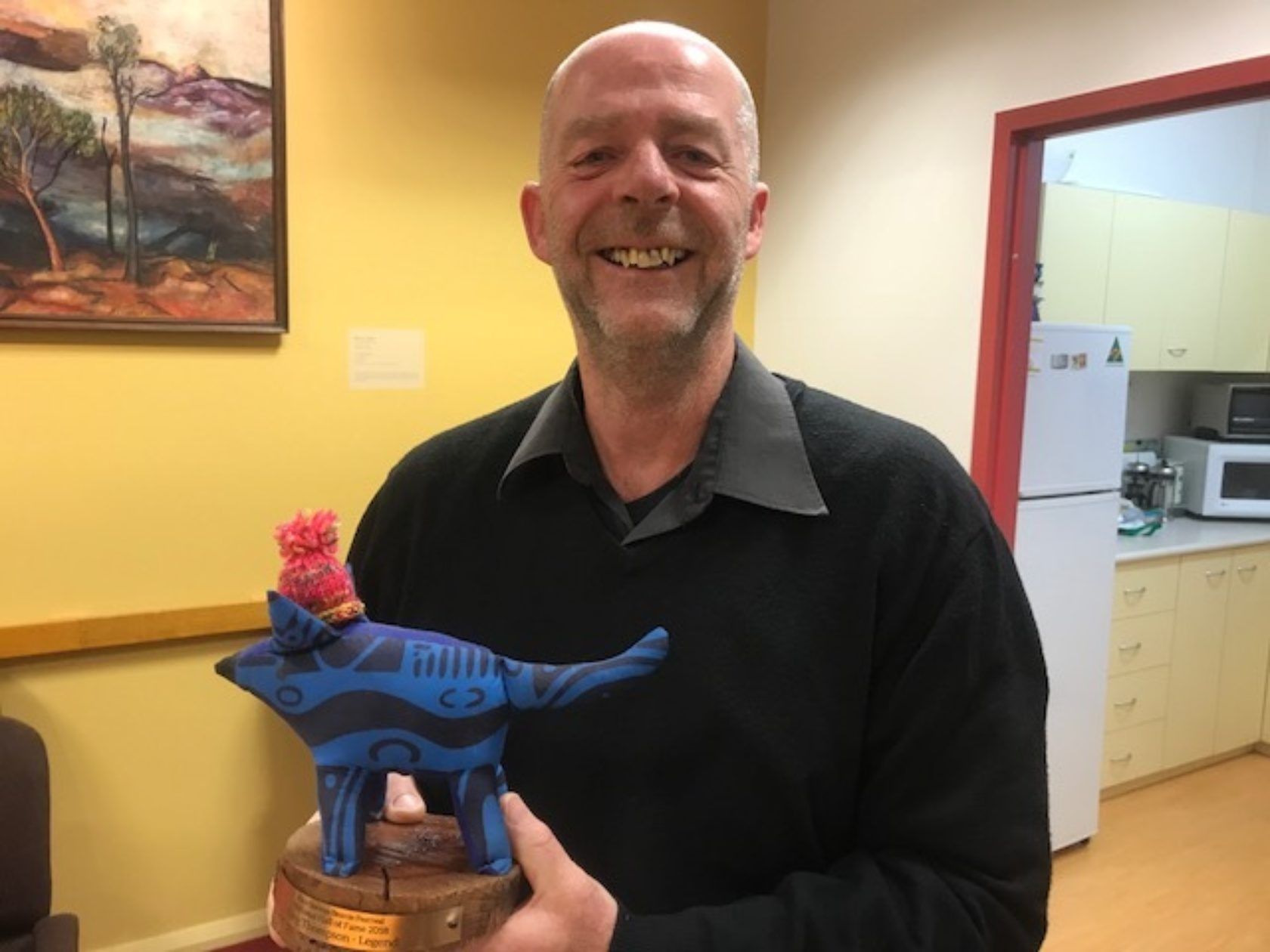 A man is holding a statue of a dog with a bird on its back.