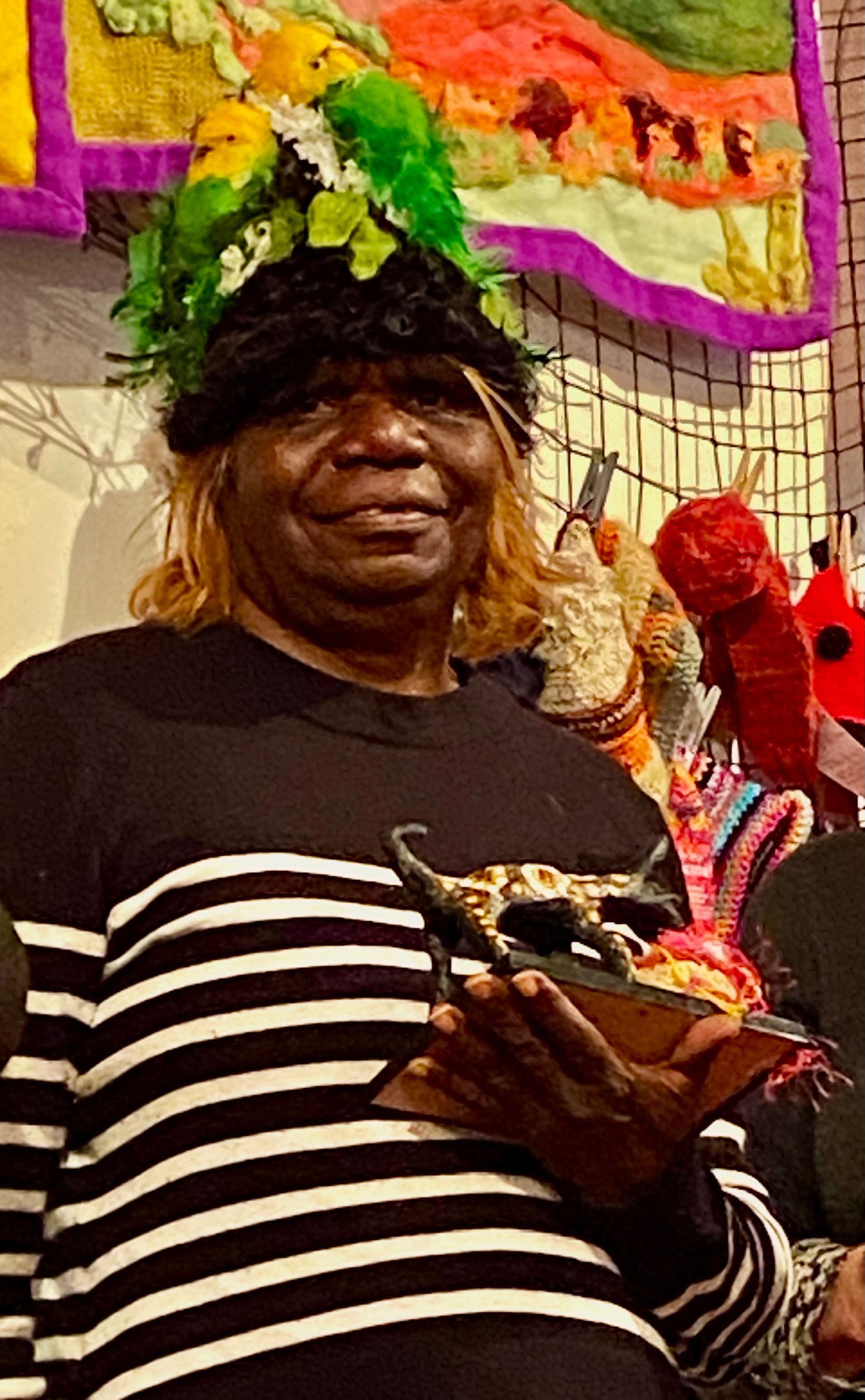 A woman in a striped shirt is holding a mask in her hands.