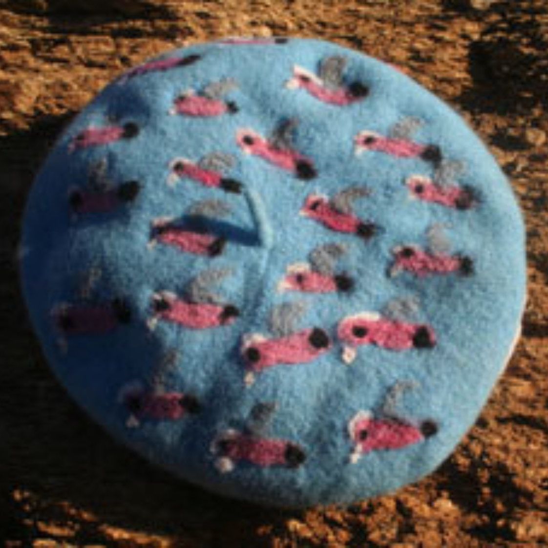 A blue beret with pink flamingos on it
