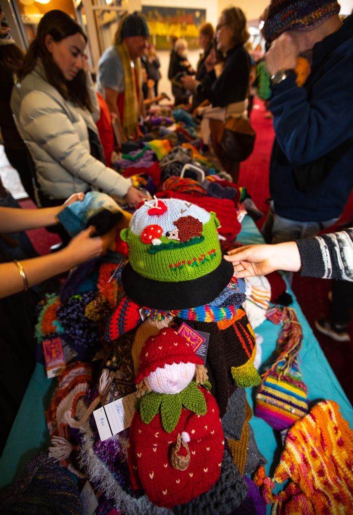 A group of people are standing around a table looking at hats.
