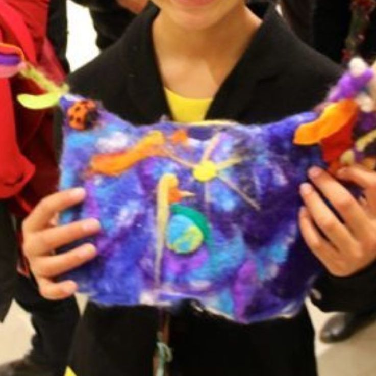 A young girl is holding a piece of art in her hands