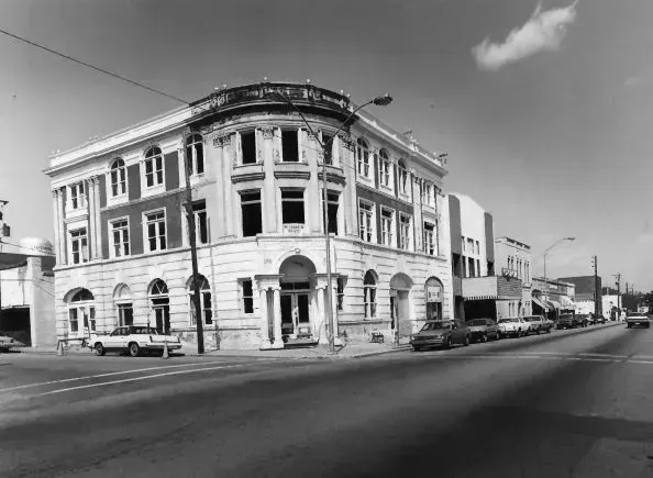 Historic corner building, Beaux-Arts style, with arched windows and detailing on a street in black and white.