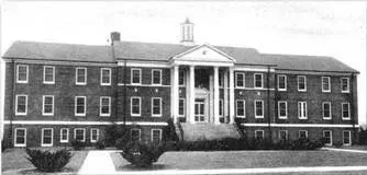 Brick building with columns and many windows, likely a school or institutional building.