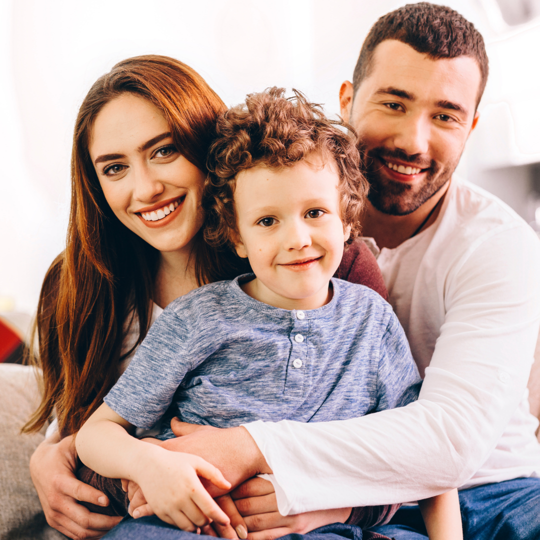 Smiling family of three hugging close together on a white background
