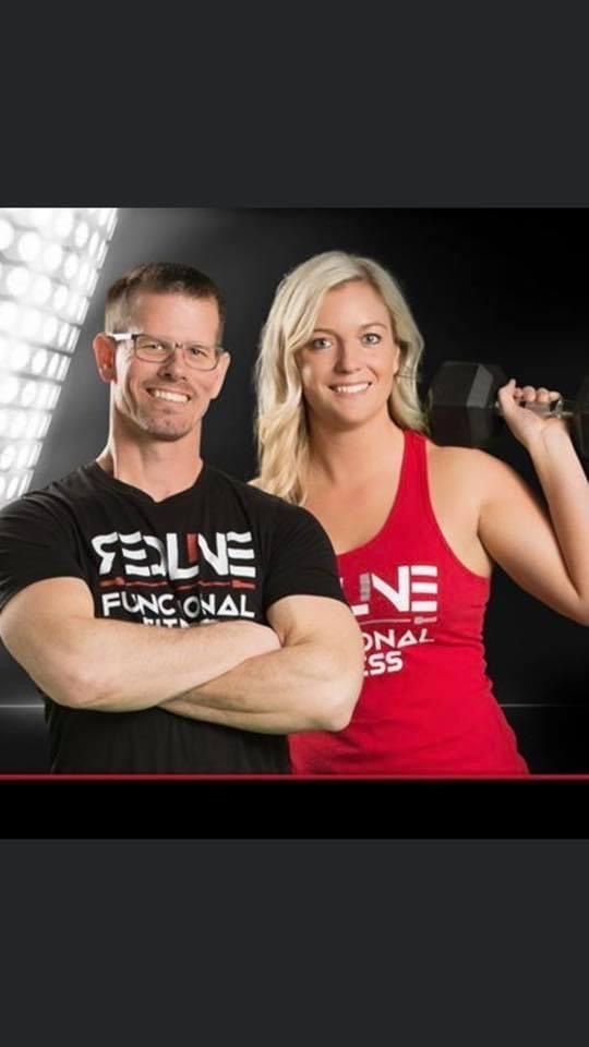 Two Redline Functional Fitness in Durant, Oklahoma fitness coaches posing with dumbbells, wearing black and pink workout shirts against a dark studio background