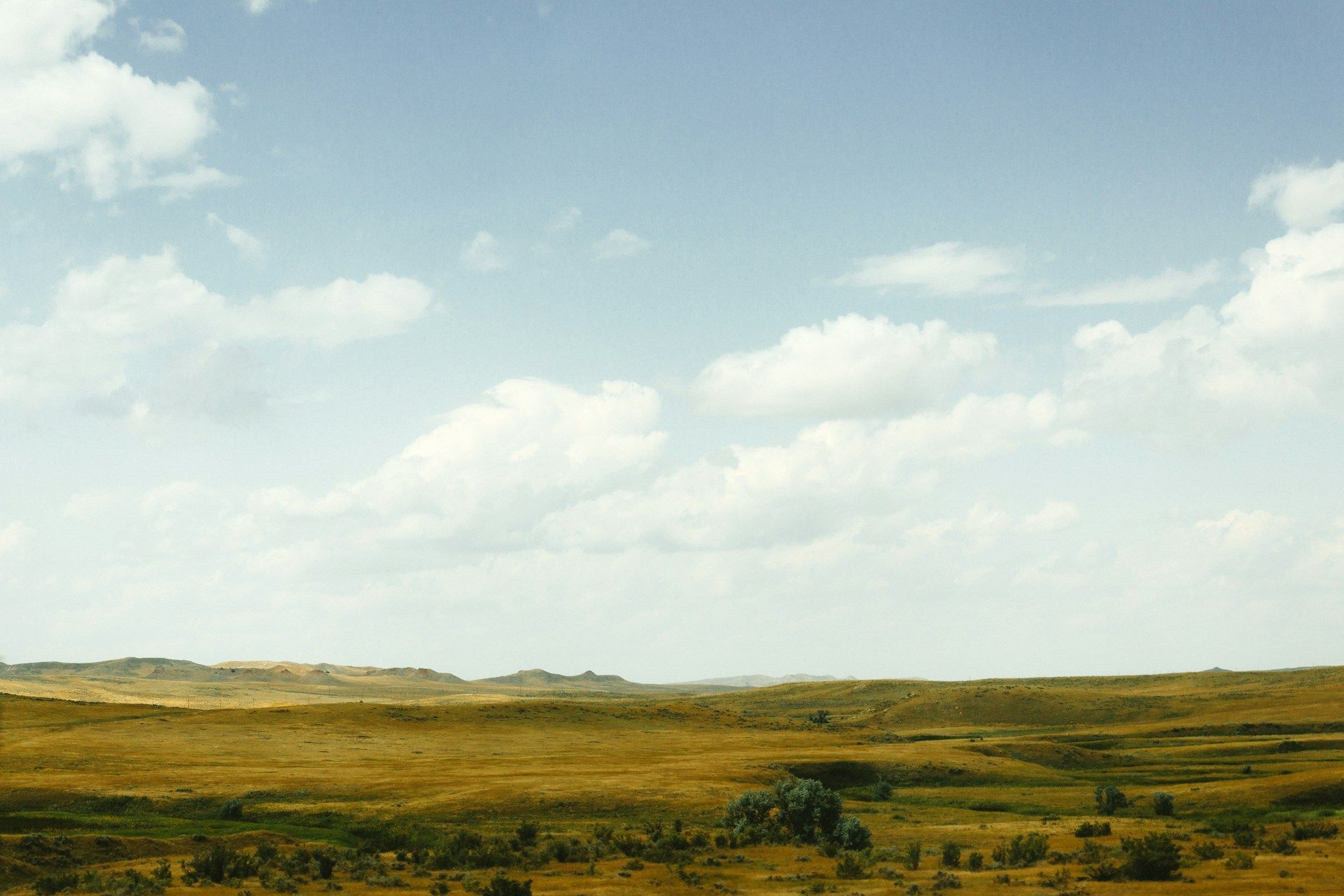 Open grassy plains under a pale blue sky with scattered clouds