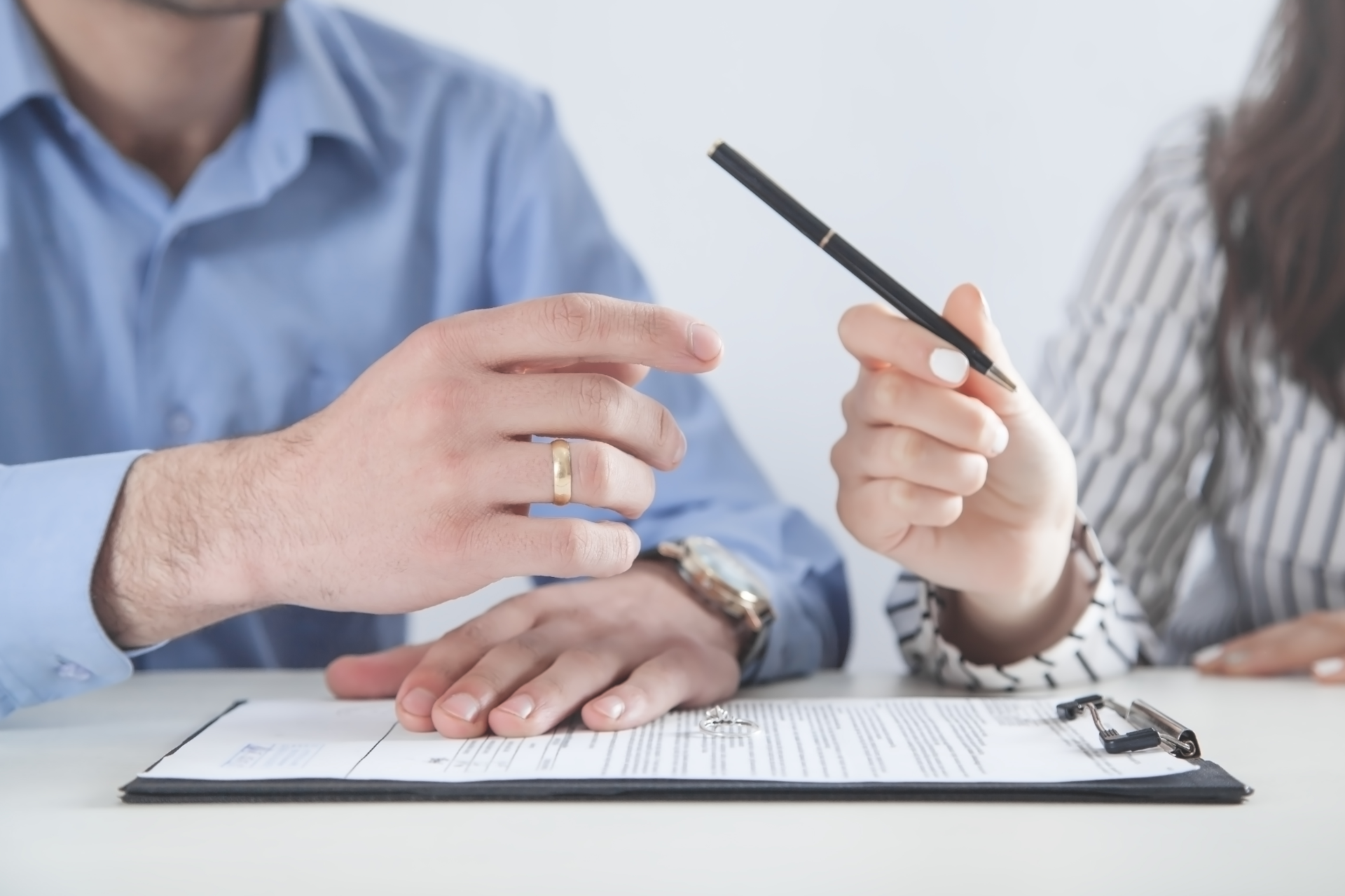 Two people discussing a document, one pointing with a pen over a clipboard on a desk.
