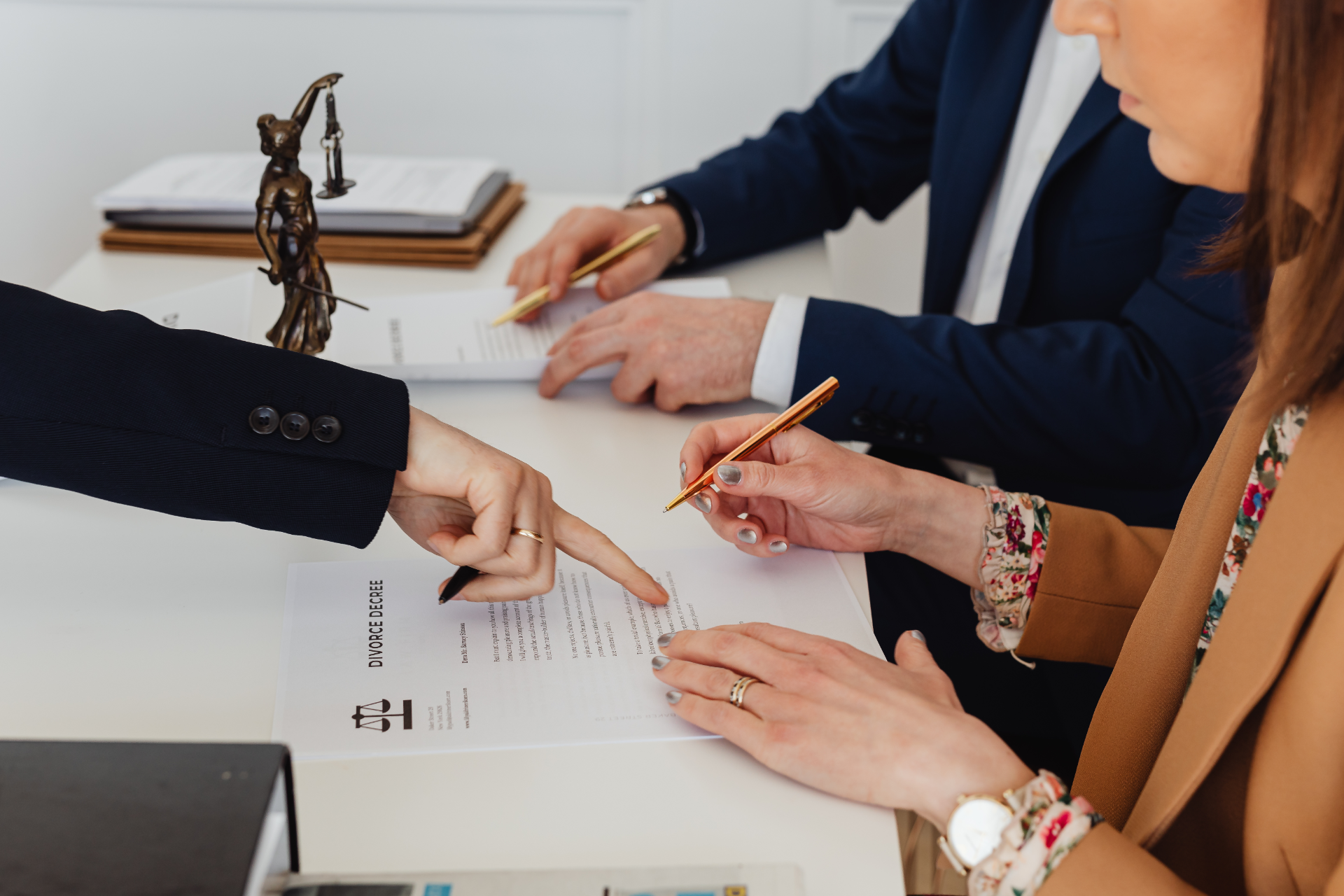 Hands pointing and signing a document during a business meeting at a desk