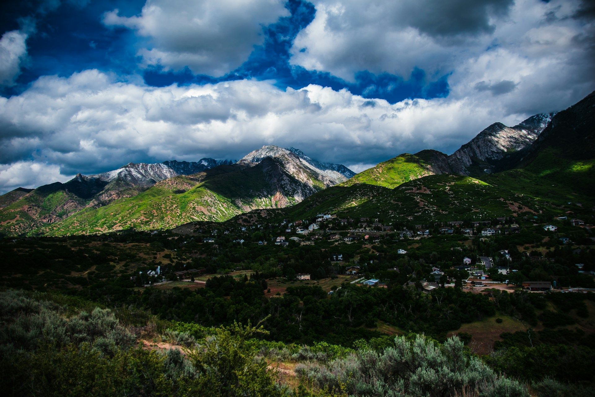 Mountain valley with sunlit green hills under dramatic cloudy sky