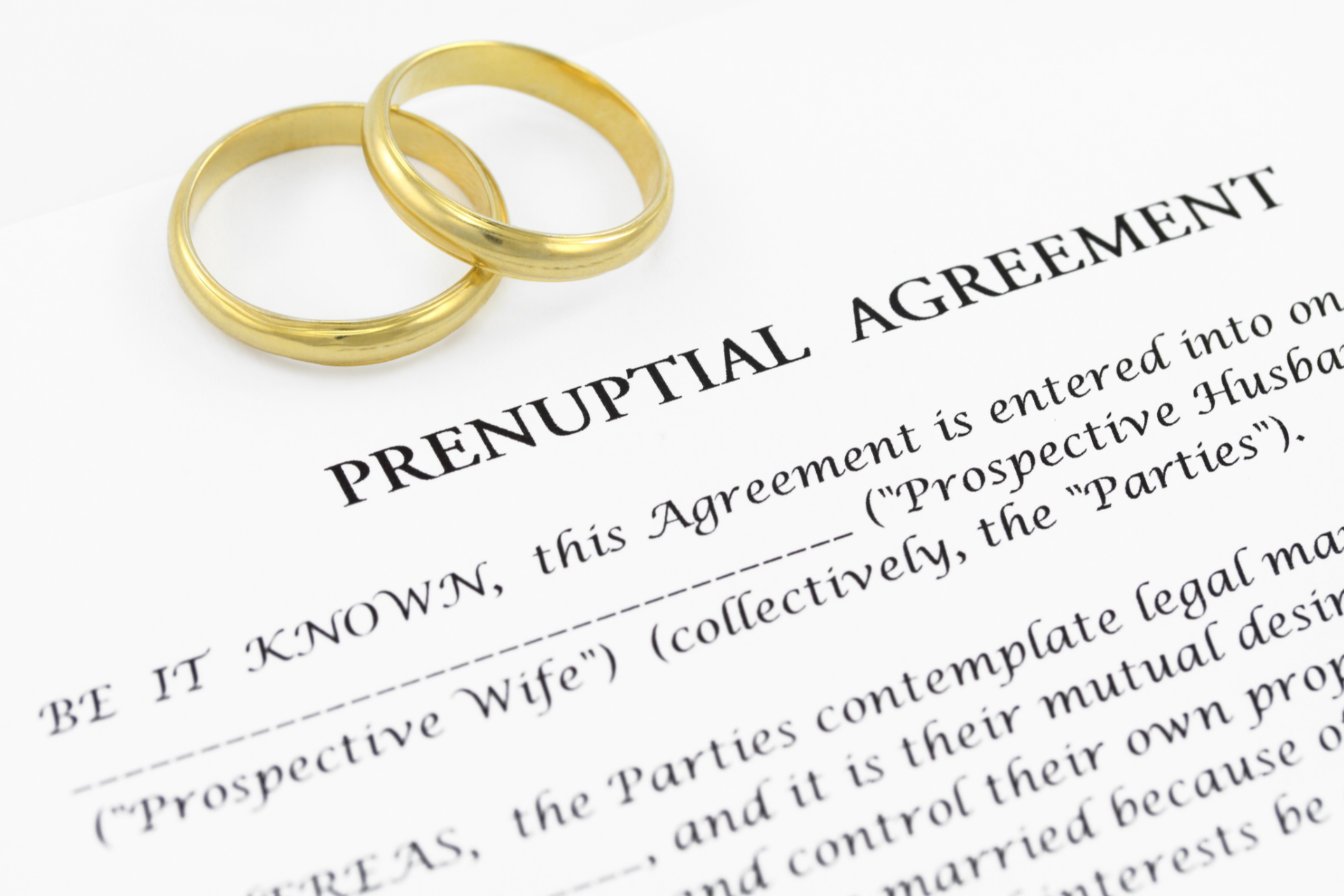 Two gold wedding rings on a prenuptial agreement document