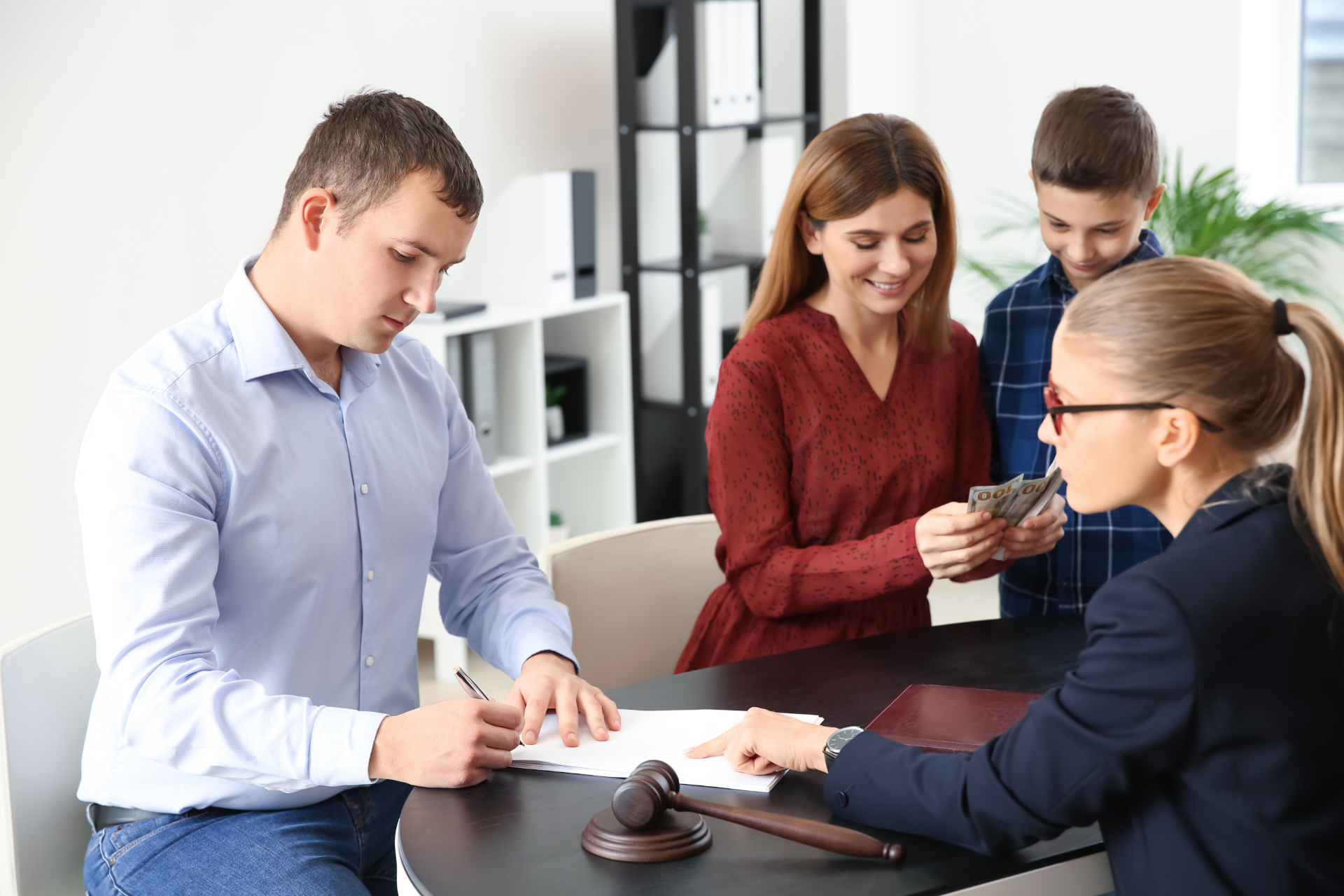 Four people in a meeting reviewing papers across a desk, with a gavel in the foreground.