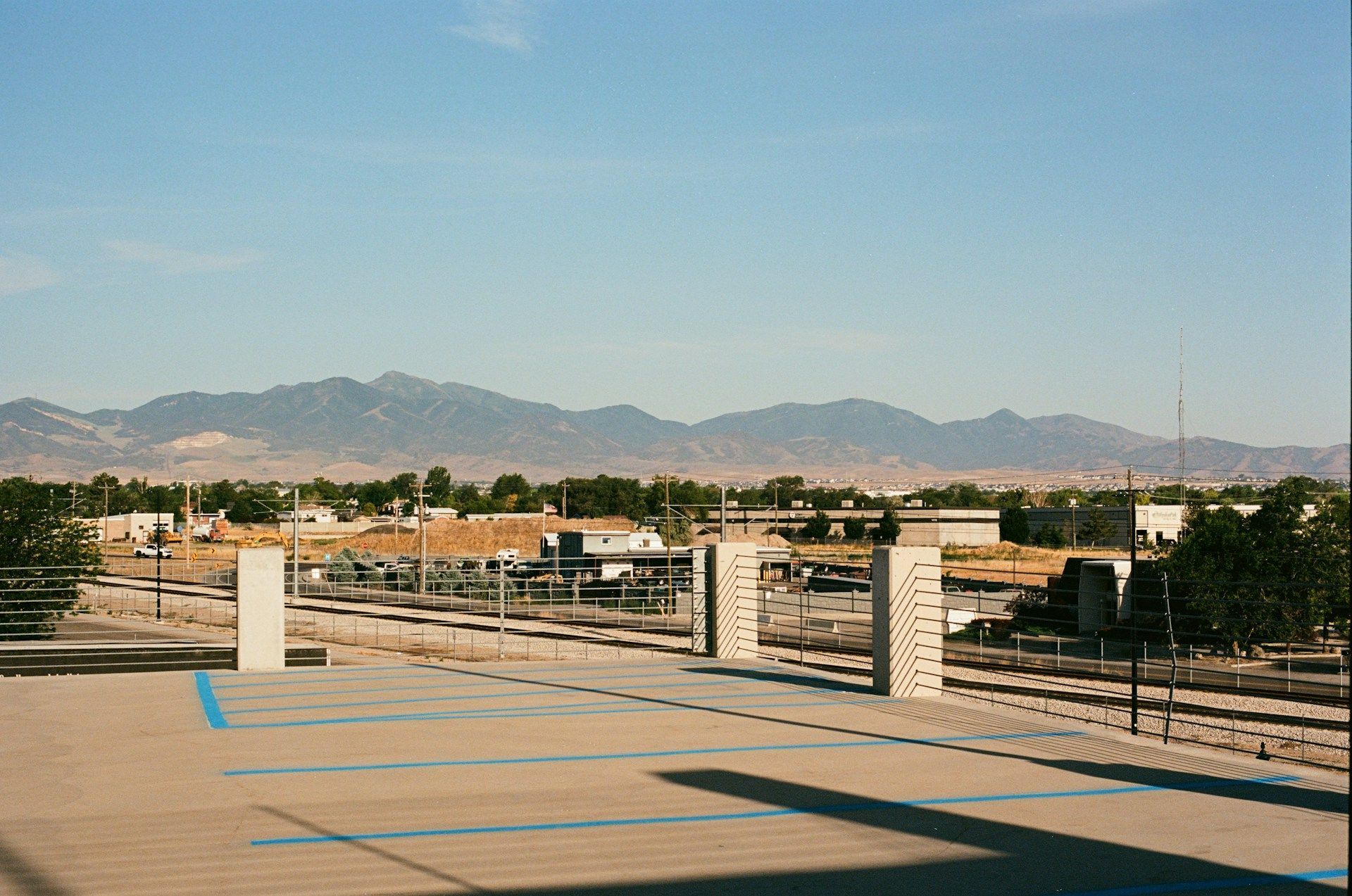 Empty rooftop parking lot with mountains in the distance under a clear blue sky