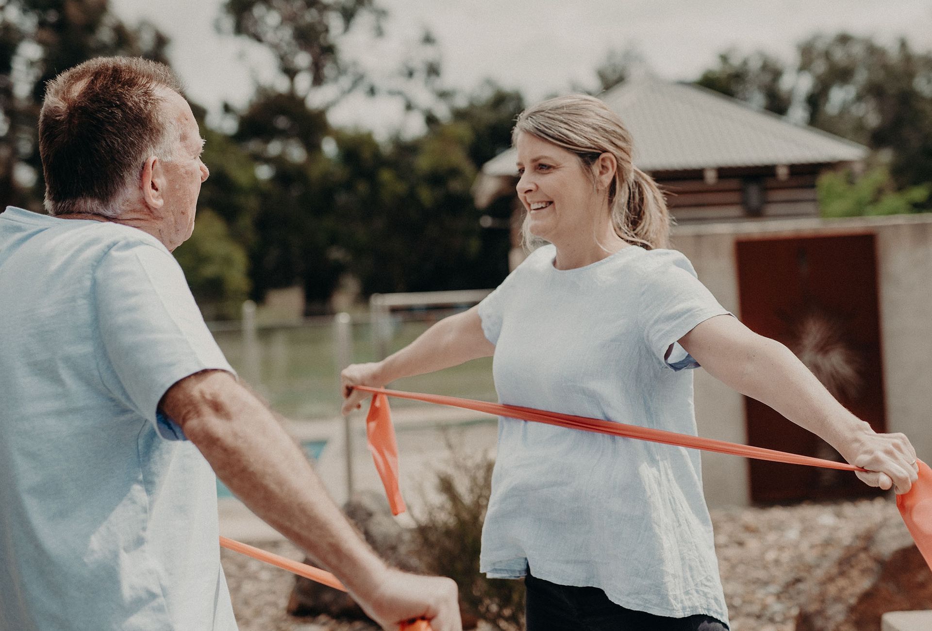 A man and a woman are doing exercises with a resistance band.
