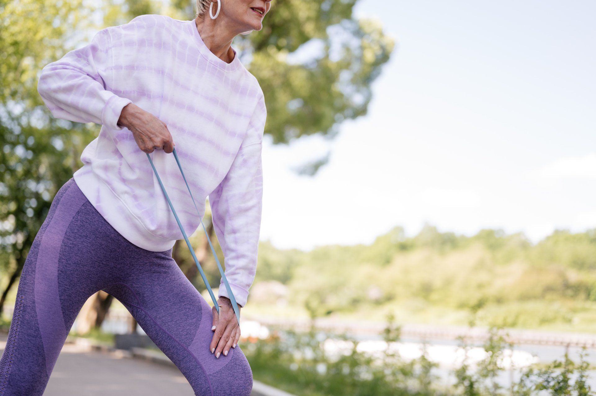 A woman is stretching her legs while walking a dog on a leash.