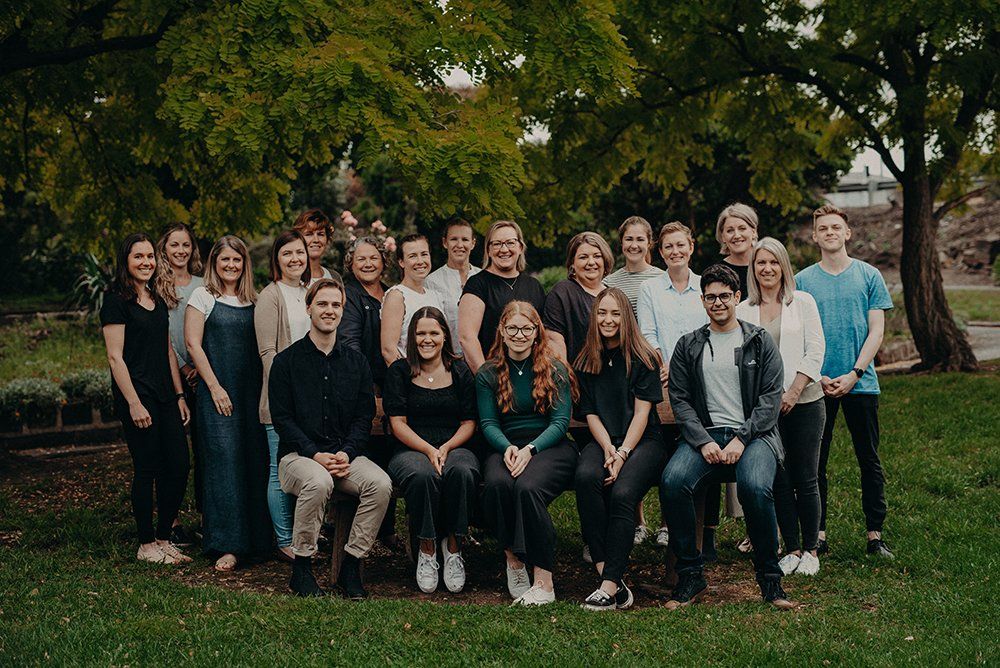A large group of people are posing for a picture in a park.