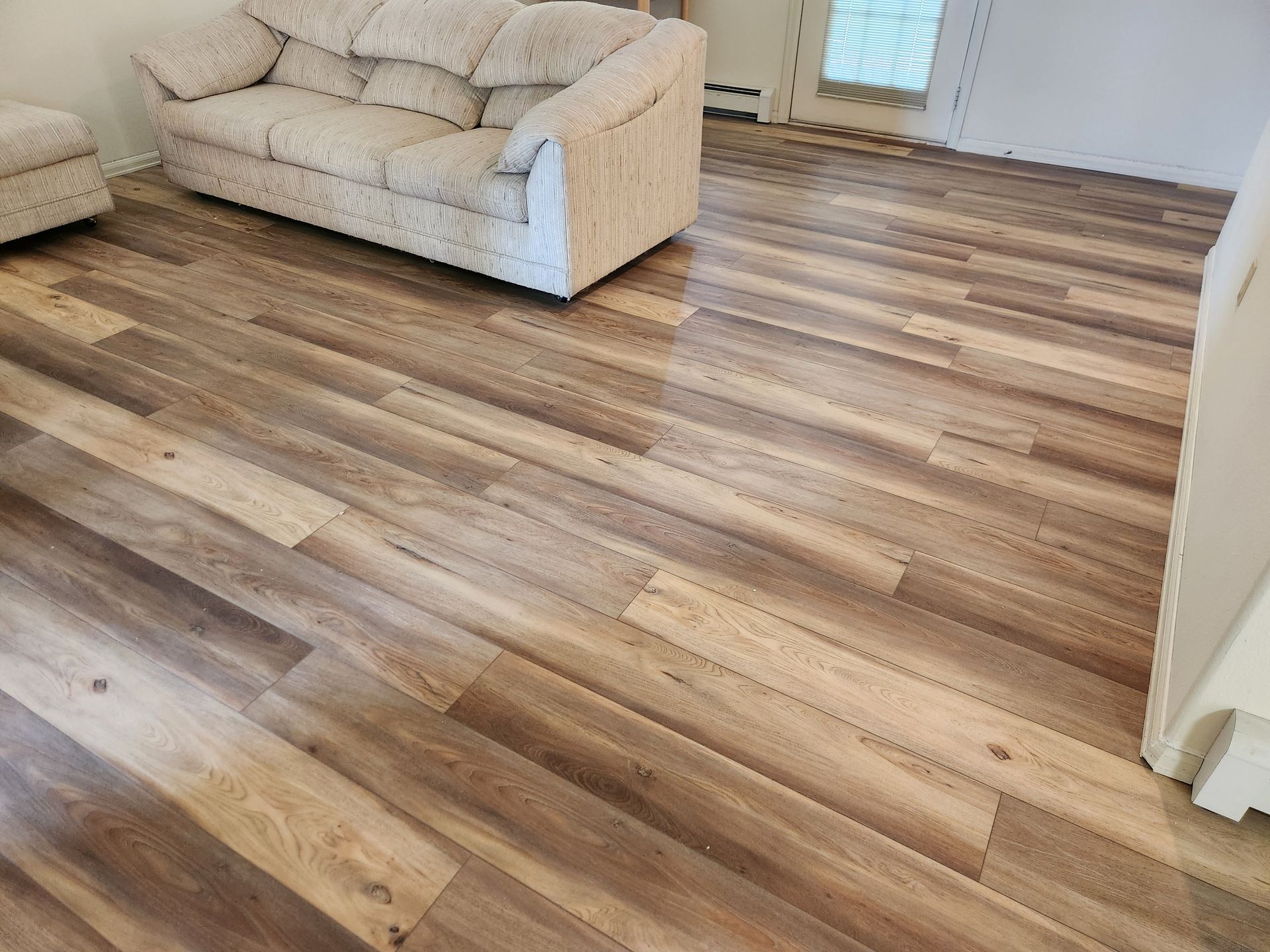 Living room with light sofas and wood-look flooring in daylight