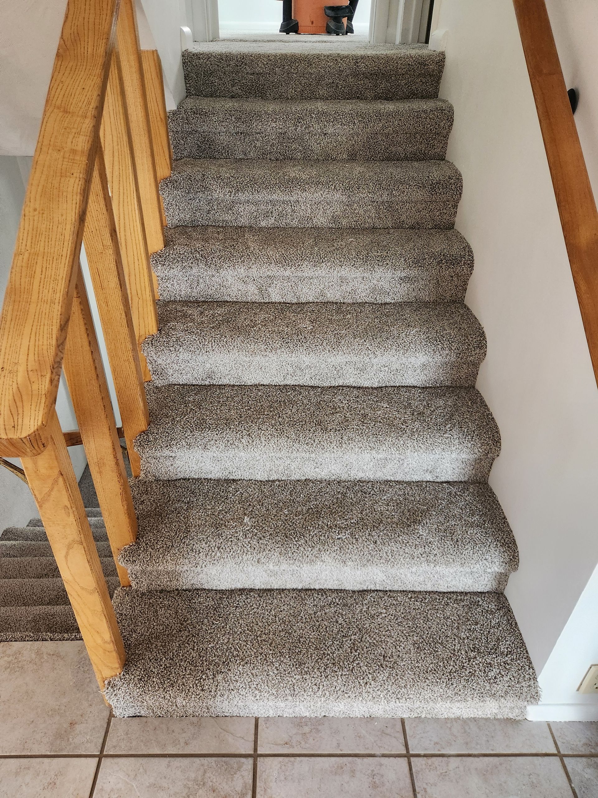 Carpeted staircase with wooden railings leading up to a small landing and window.