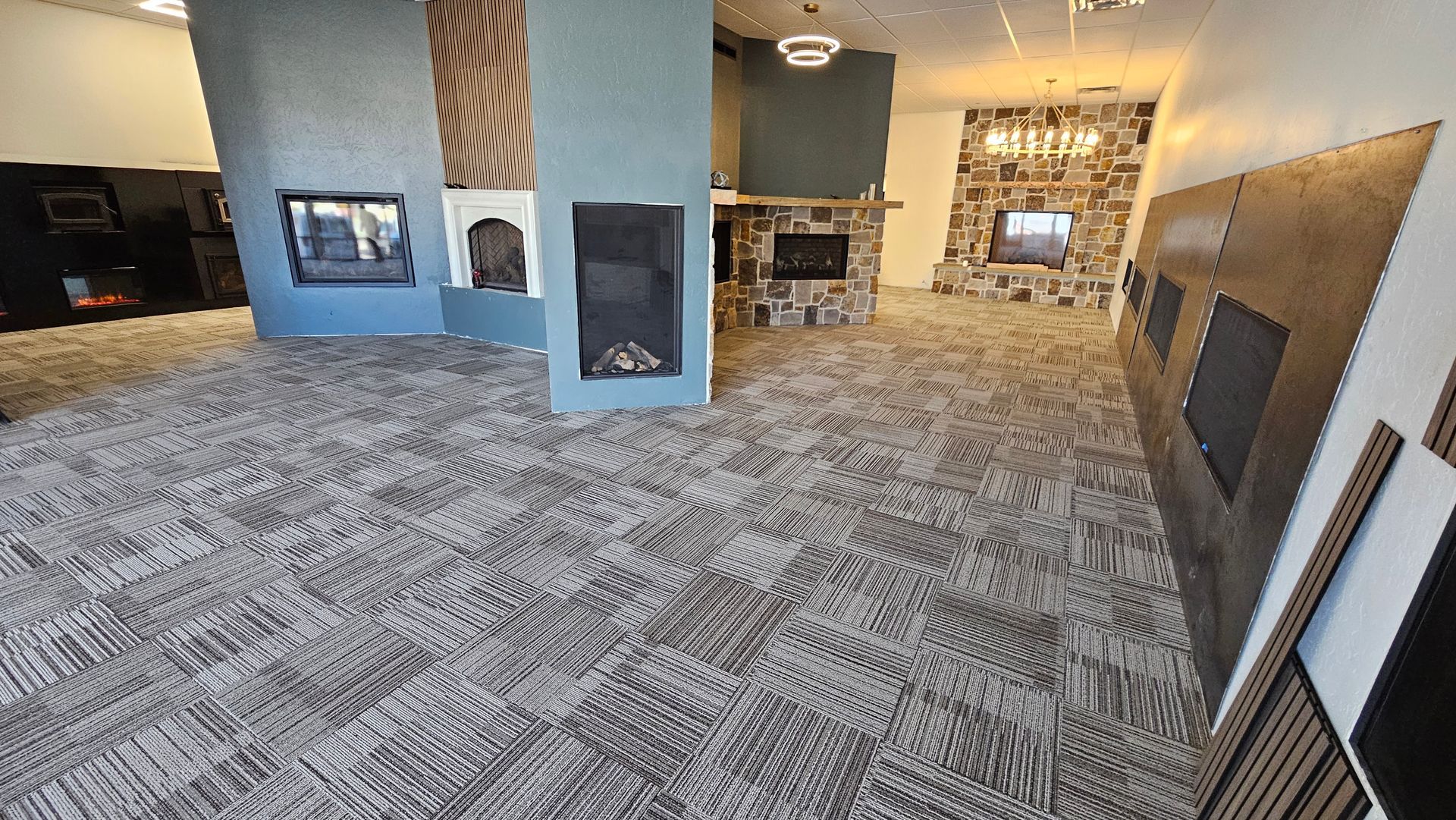 Spacious lobby with patterned carpet, fireplaces, and a blue accent wall under warm lighting.