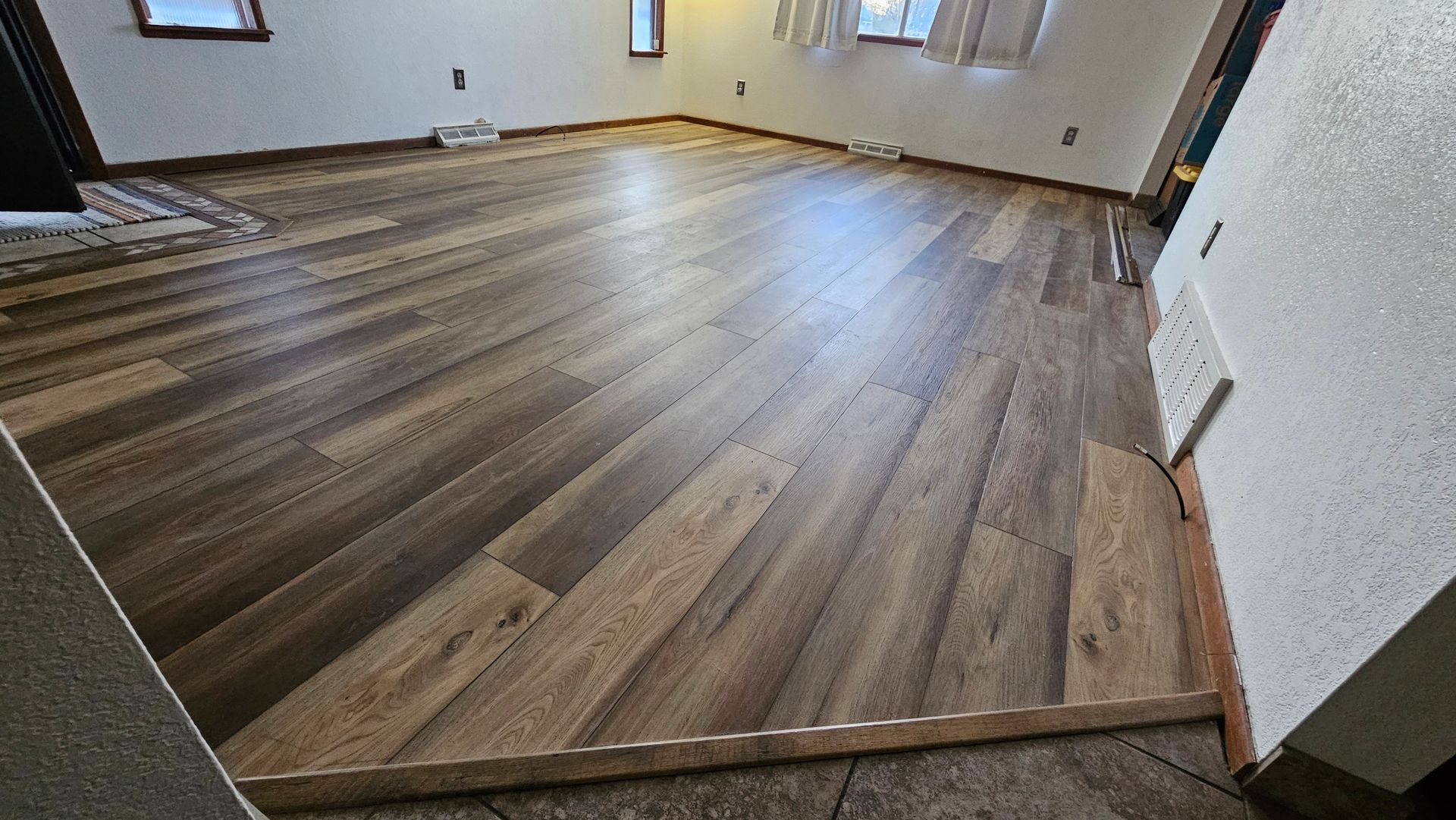 Empty room with wood-look flooring, baseboards, and white walls, viewed from a doorway