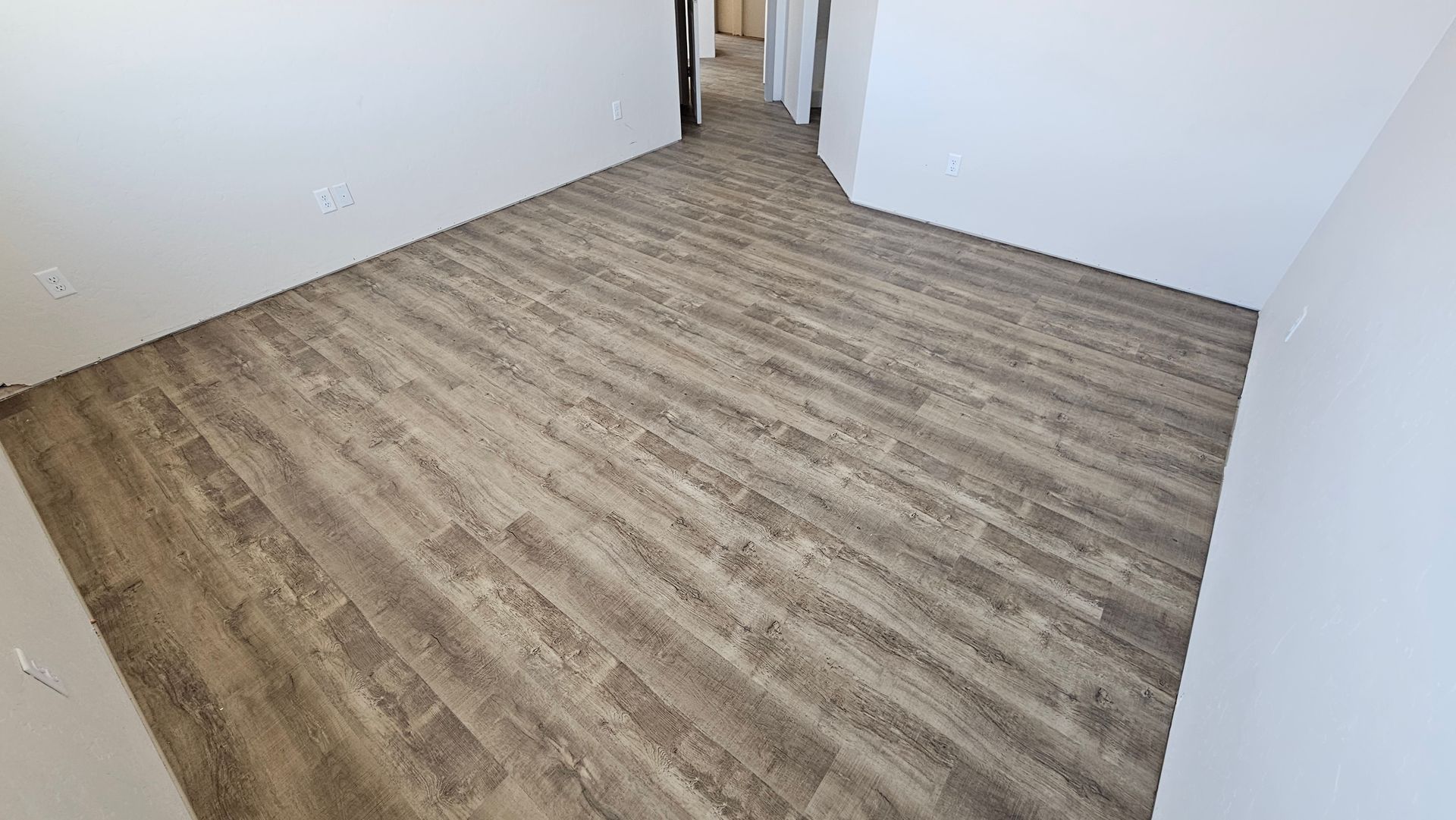 Empty room with wood-look flooring, white walls, and a doorway in the back.