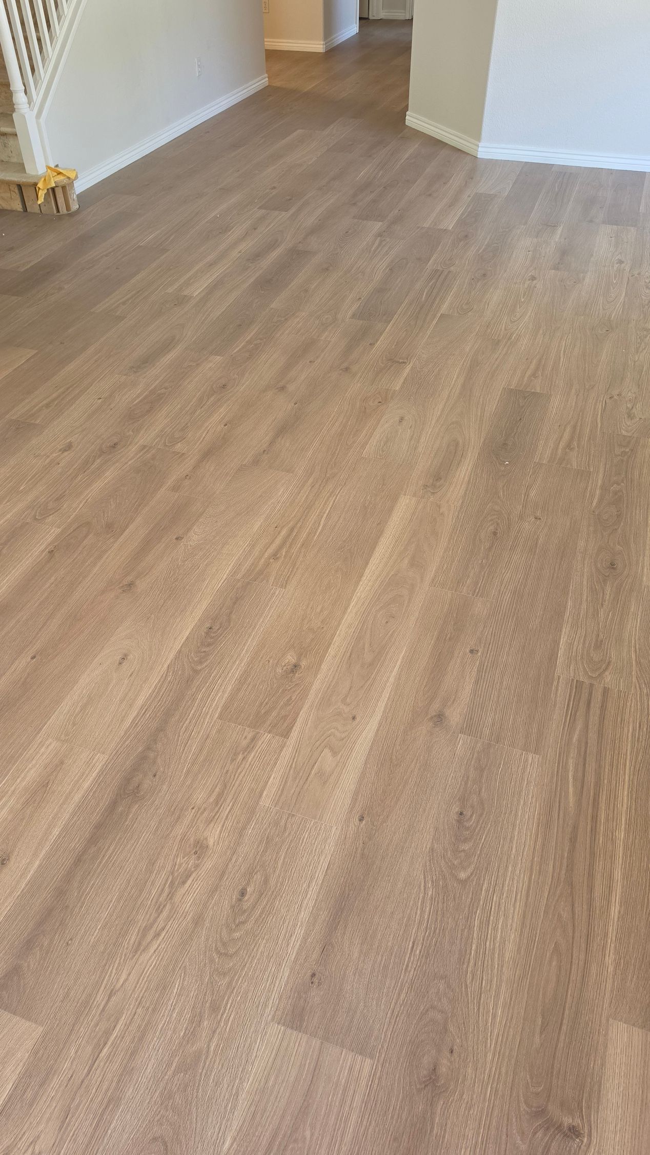 Empty room with light wood flooring and white walls, viewed from the corner.