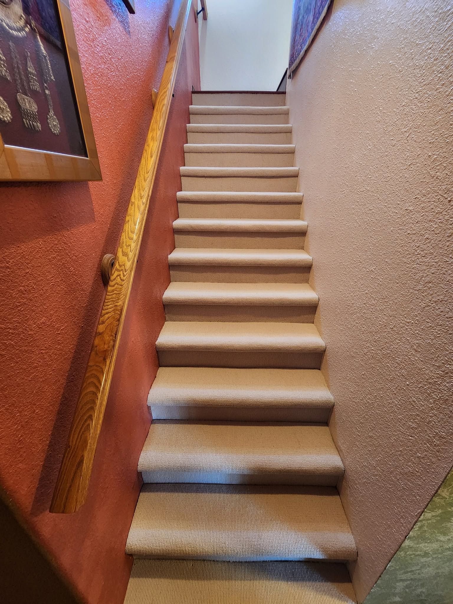 Narrow carpeted stairway with textured red and beige walls leading upward indoors