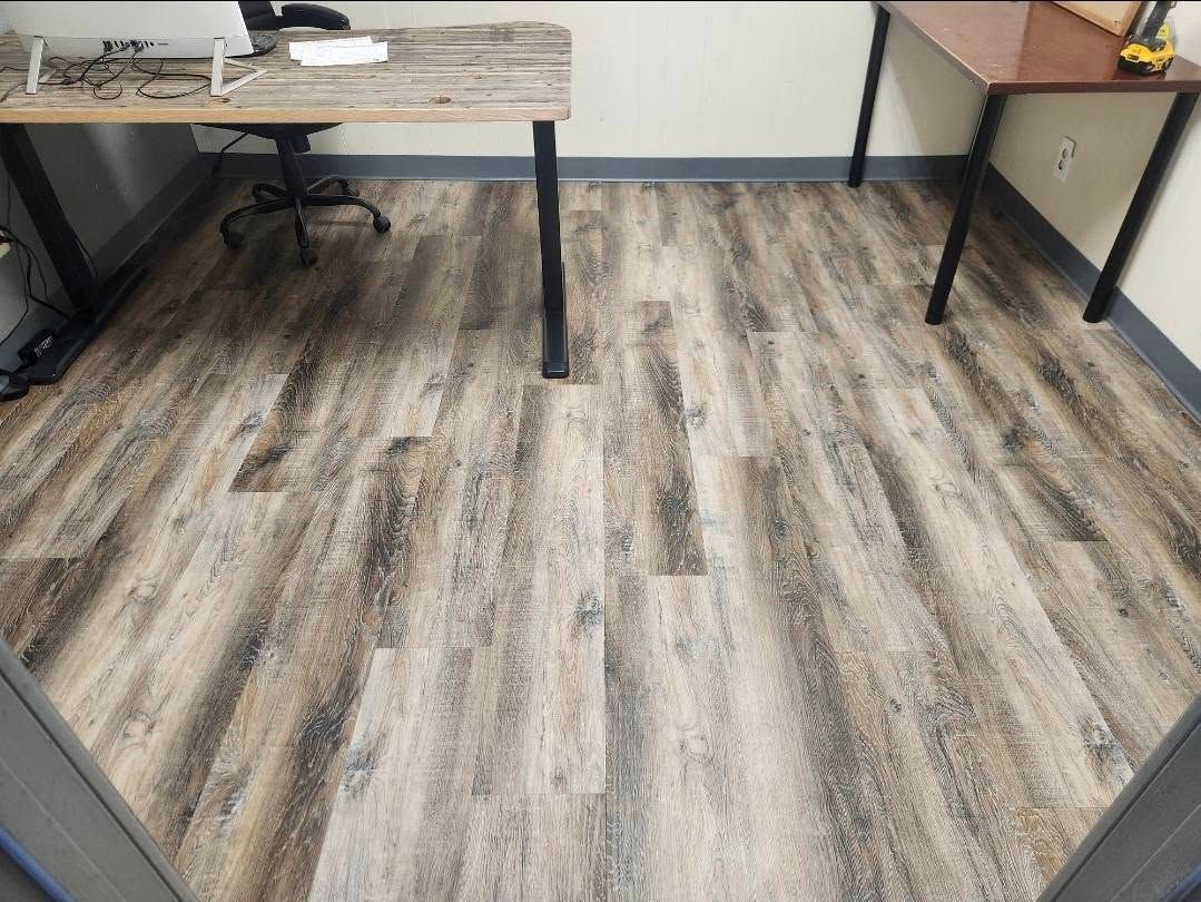 Office room with wood-look flooring, black table legs, and a beige wall.