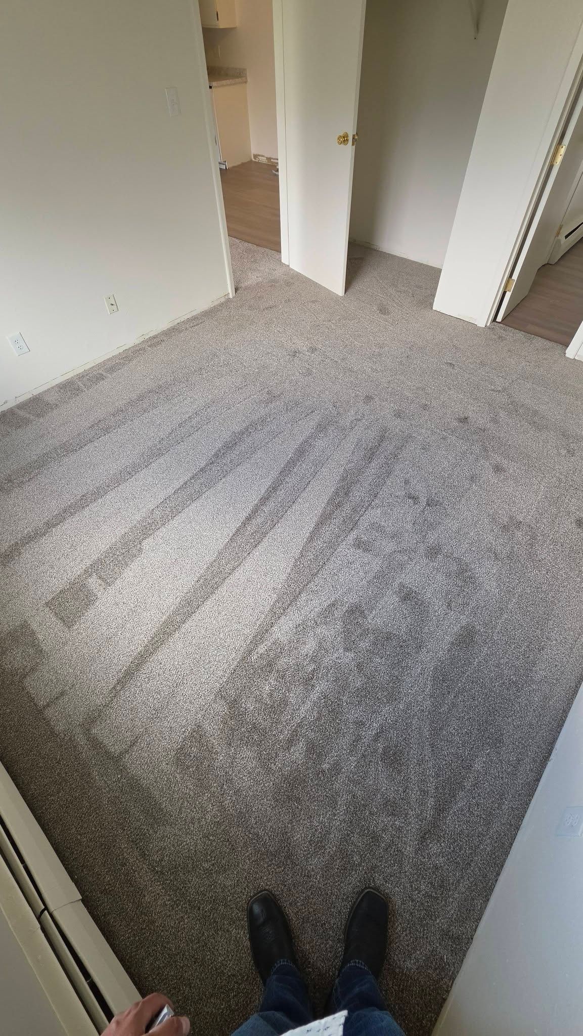 Carpeted hallway with open doors and a person’s shoes visible at the bottom edge.