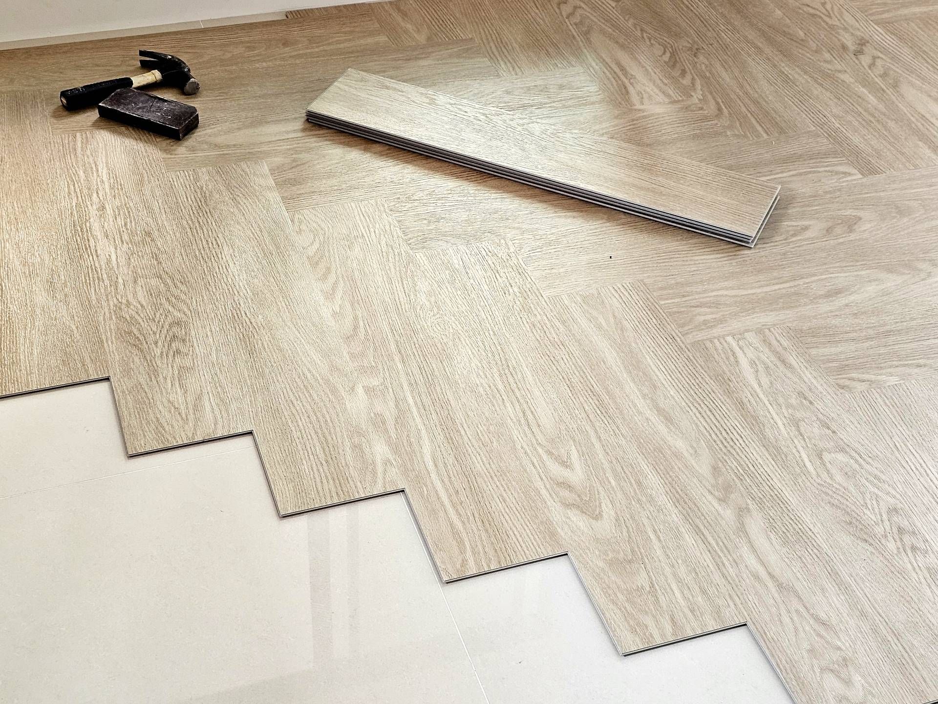 Light wood-look flooring being installed with a saw and tools on the floor