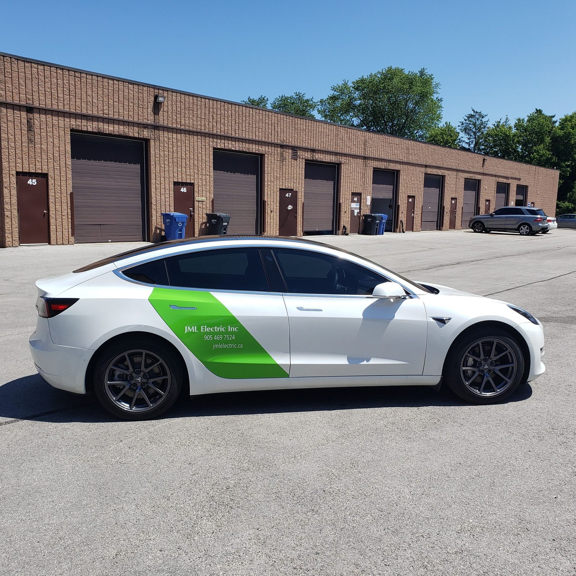 A white tesla model 3 is parked in front of a brick building