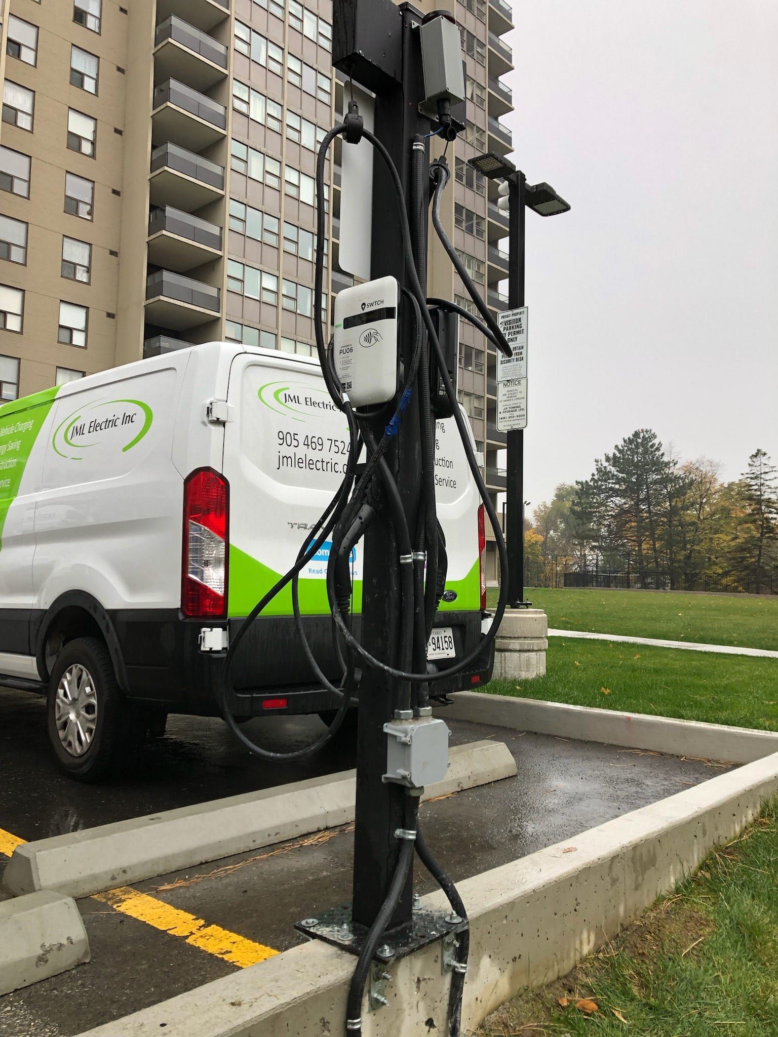 A white van is parked in a parking lot next to a pole.