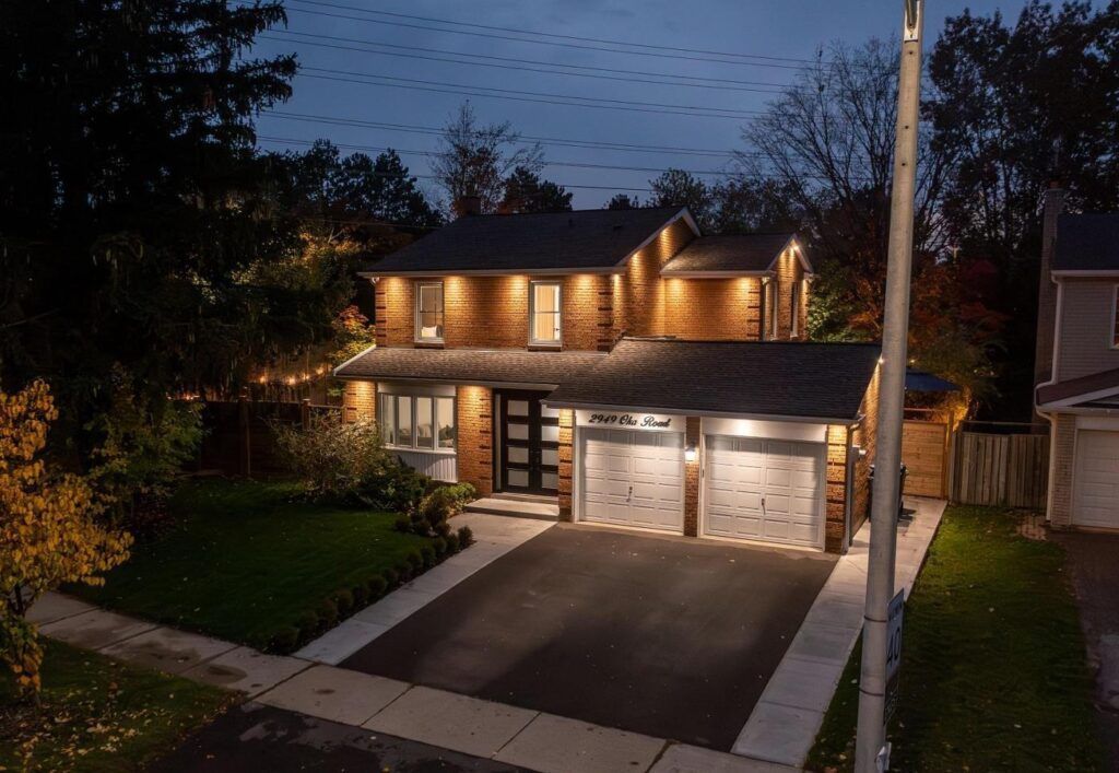 A large house with two garages is lit up at night.
