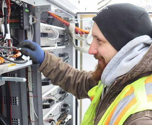 A man in a safety vest is working on a server