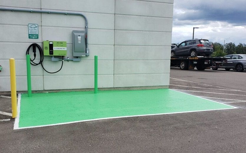 A green parking lot with a charger on the side of a building