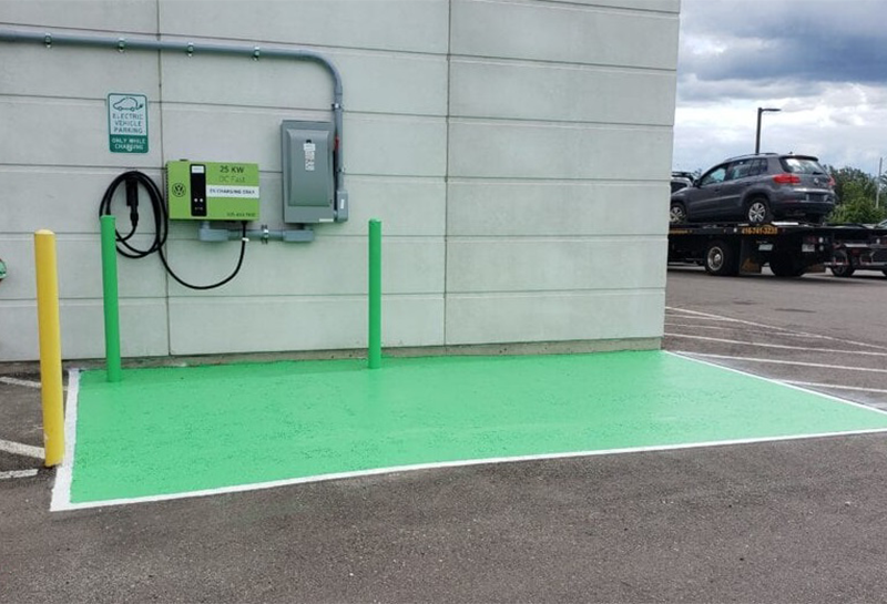 A car is parked in a parking lot next to a charging station
