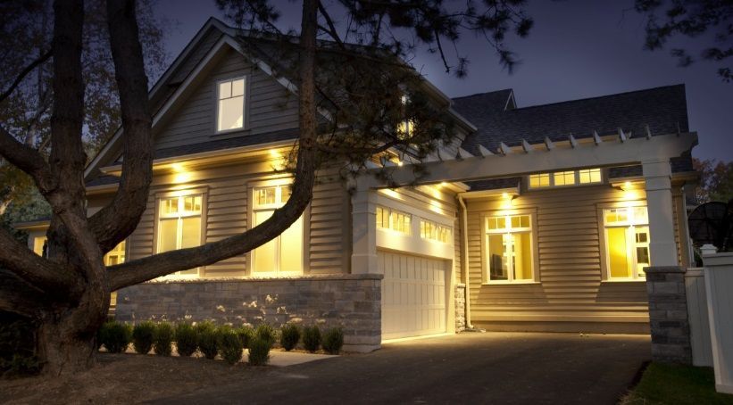 A house is lit up at night with a tree in front of it.
