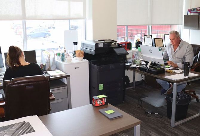 A man and a woman are sitting at desks in an office.