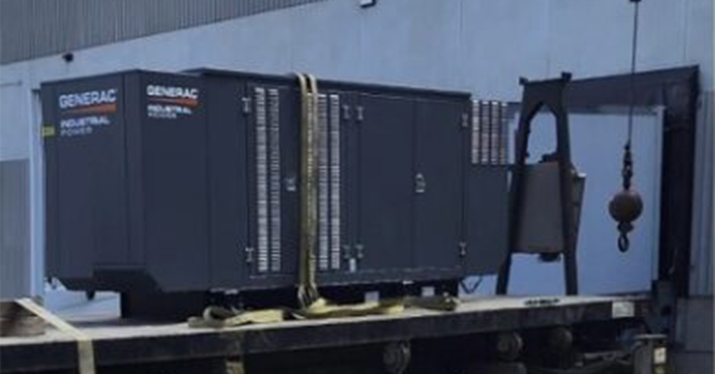 A generator is sitting on top of a train car.