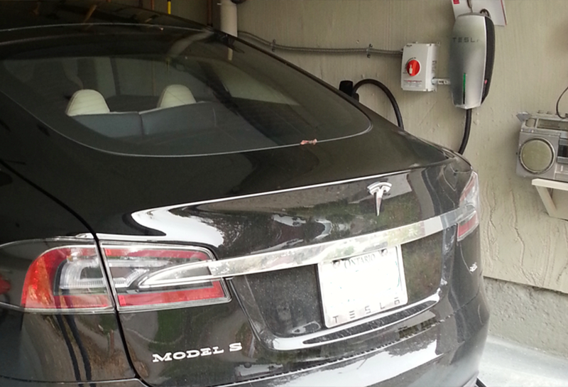 A black tesla model s is parked in a garage.