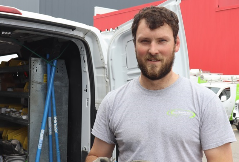 A man in a grey shirt is standing in front of a van