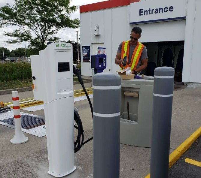 A man in a yellow vest is working at the entrance of a gas station